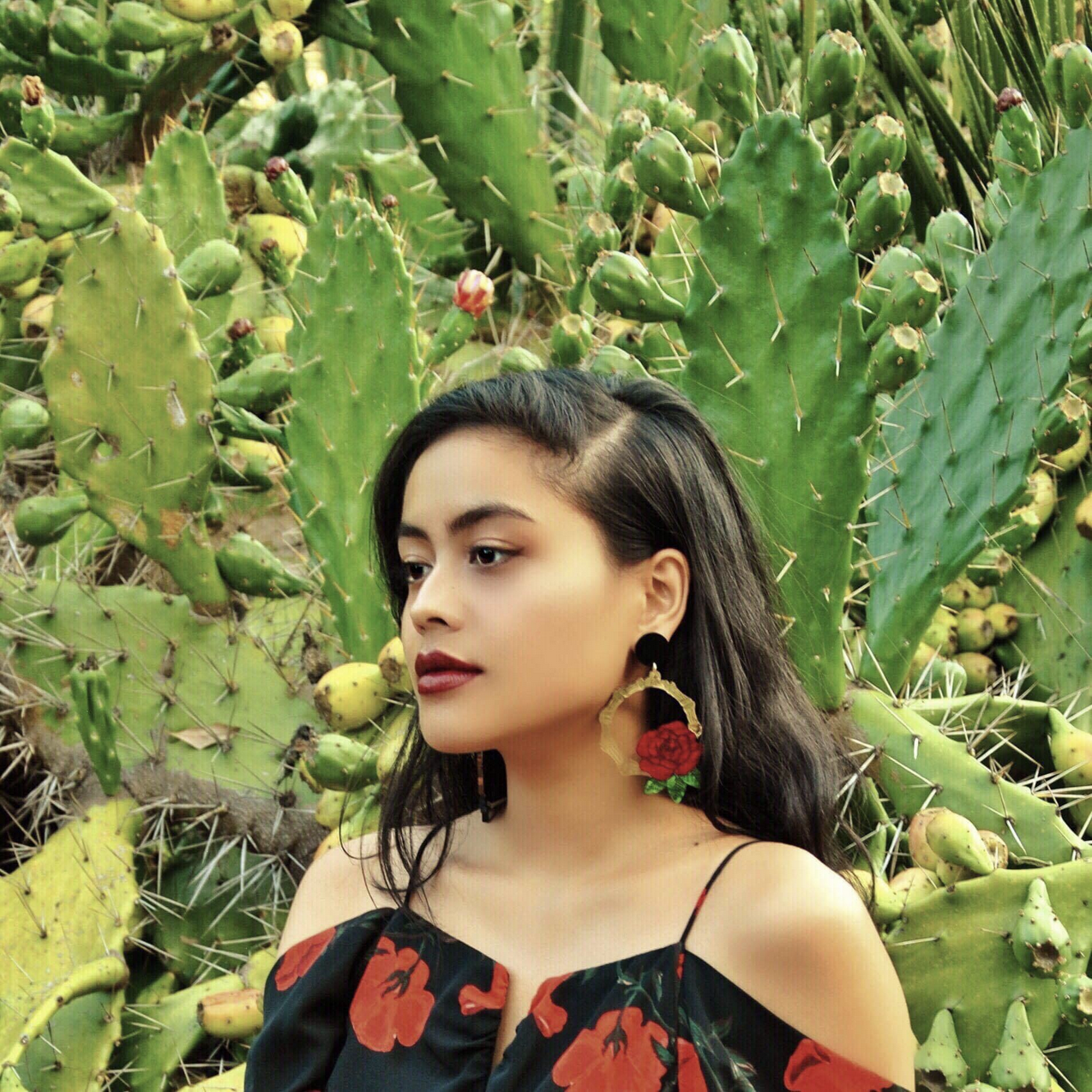 Shot of Eunice looking to the left, in front of a garden of cacti